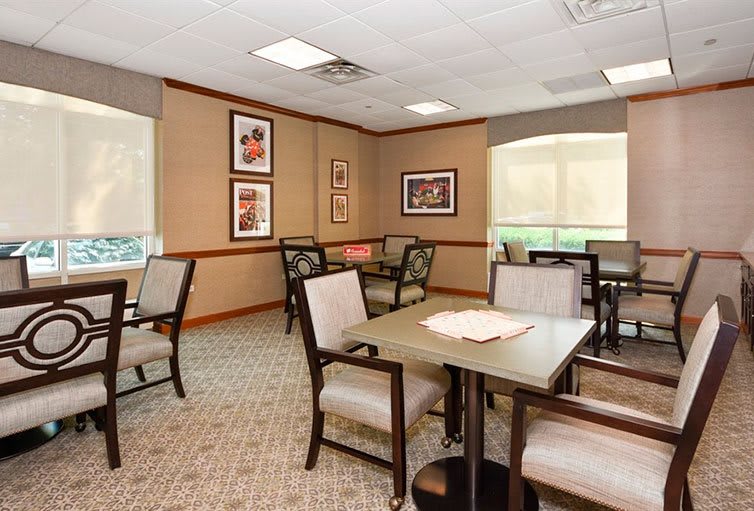 A cozy dining room with several tables and chairs, decorated with framed artwork on the walls.