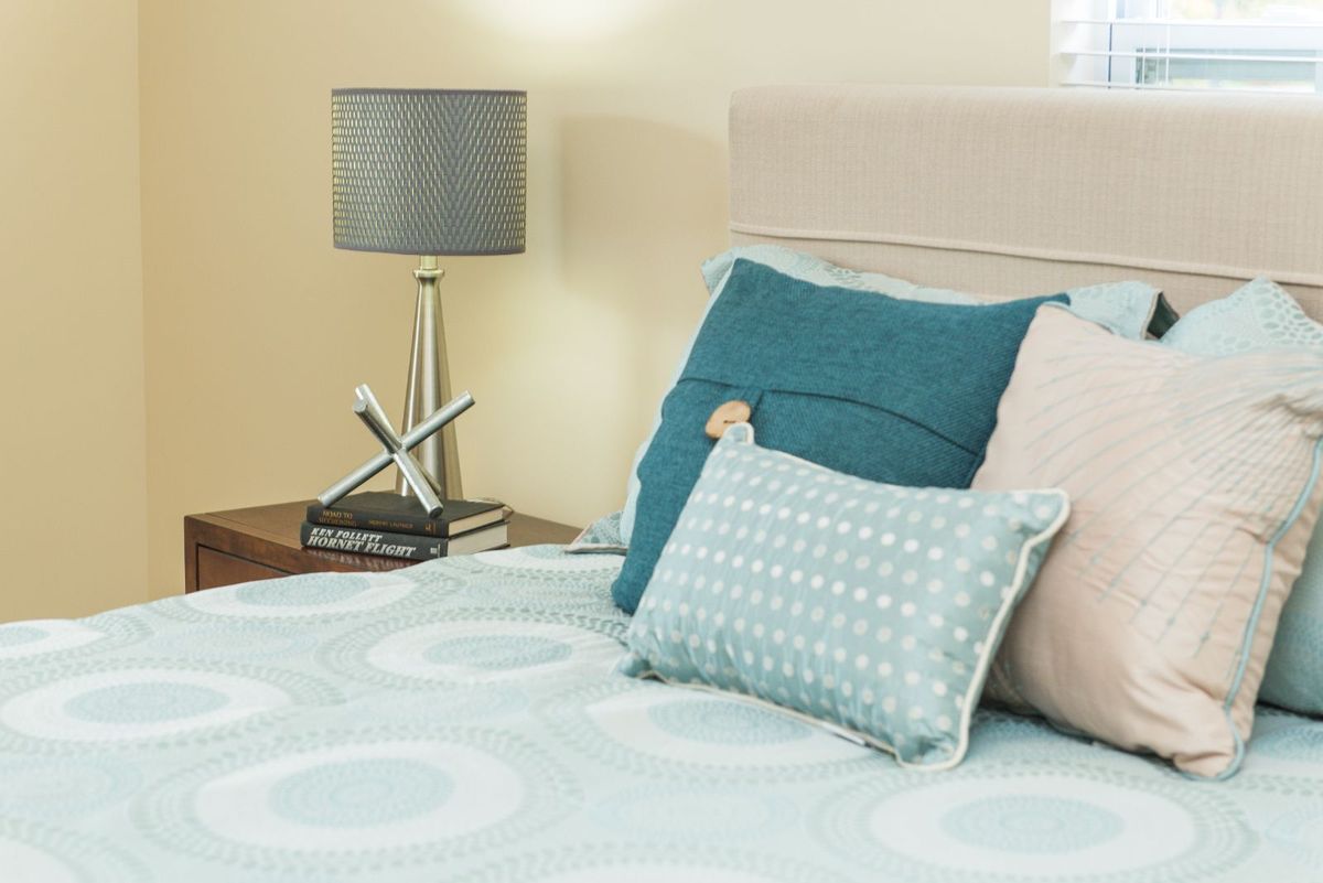 A cozy bedroom setting with decorative pillows and a stylish bedside lamp.