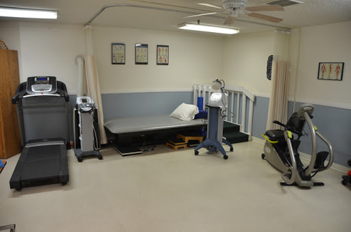 A therapy room equipped with various rehabilitation equipment and exercise machines.