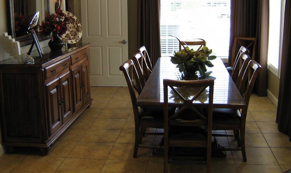 A cozy dining room with a wooden table and chairs, decorated with a floral centerpiece.