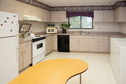 A clean and organized kitchen with a view, featuring modern appliances and a wooden table.