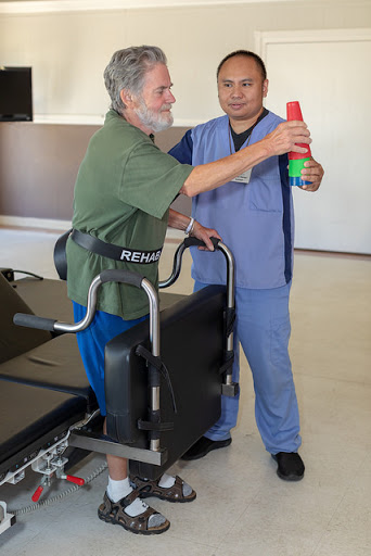 A healthcare professional assists a patient in a rehabilitation exercise.