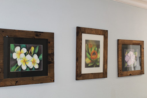 A beautiful display of floral-themed paintings in rustic frames.
