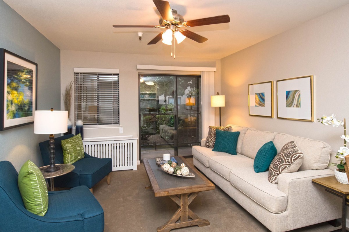 A cozy living room with a beige sofa, coffee table, and ceiling fan.