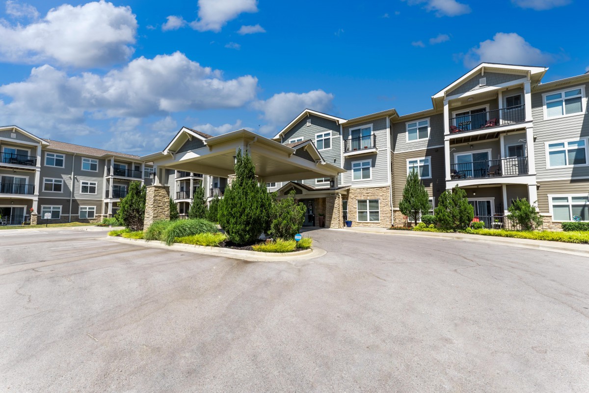 A modern apartment building with well-maintained landscaping under a clear blue sky.