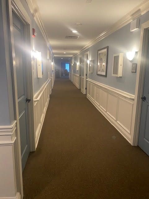 A long, well-lit hallway with blue walls and multiple doors on each side.
