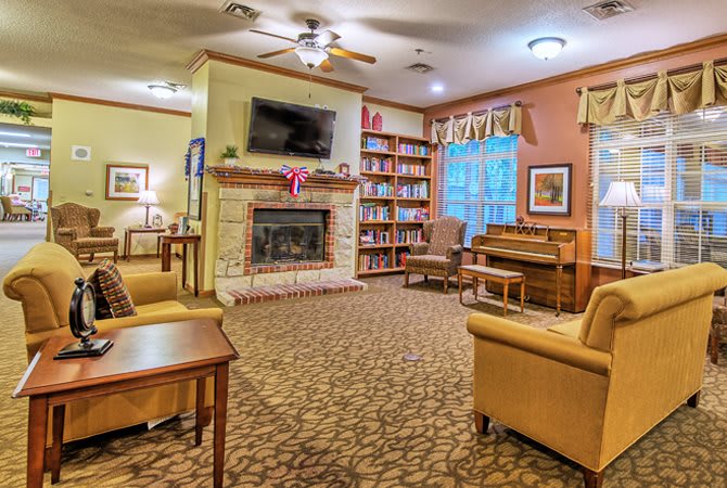 A cozy living room featuring a fireplace, bookshelves, and a piano with comfortable seating.