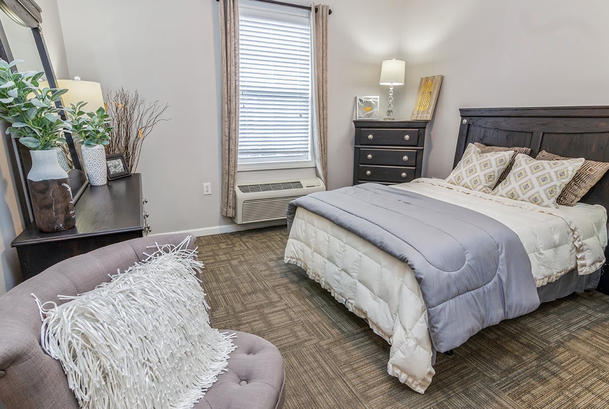 A cozy bedroom with a neatly made bed, dresser, and decorative elements.