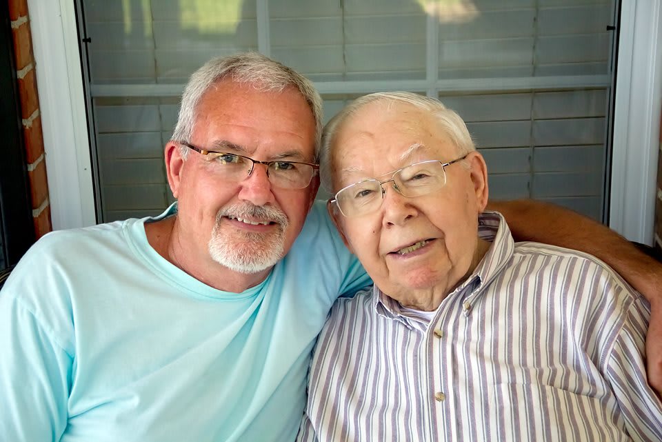 Two men smiling and embracing, capturing a moment of togetherness.