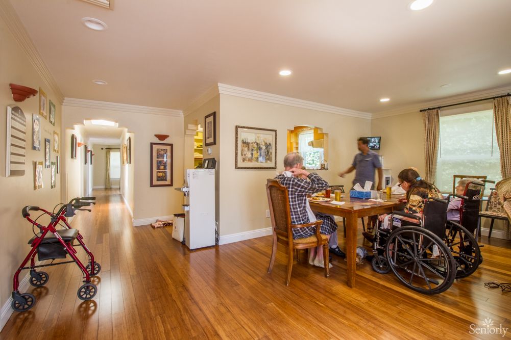 A family gathering in a cozy dining room, with some members in wheelchairs around the table.