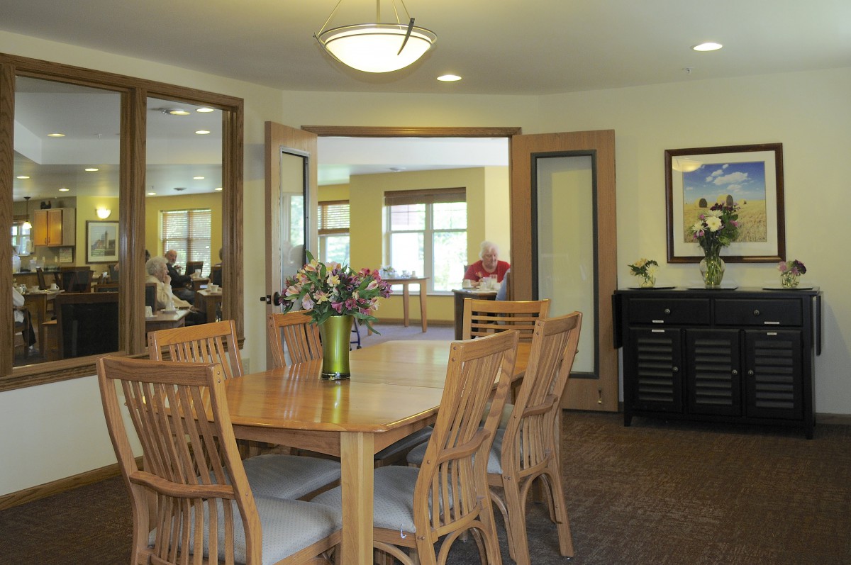 A wooden dining table surrounded by chairs in a well-lit room with decorative elements.