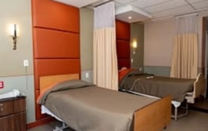 A hospital room with two beds separated by a curtain.