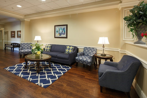 A cozy living room setup featuring a blue sofa, patterned armchair, and a stylish coffee table, complemented by warm lighting and elegant decor.
