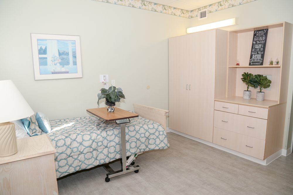 A clean and minimalist hospital room featuring a bed, wardrobe, and bedside table.