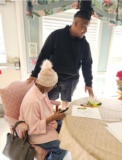 A warm moment of interaction between an elderly person and a younger individual, sharing a conversation at a table.