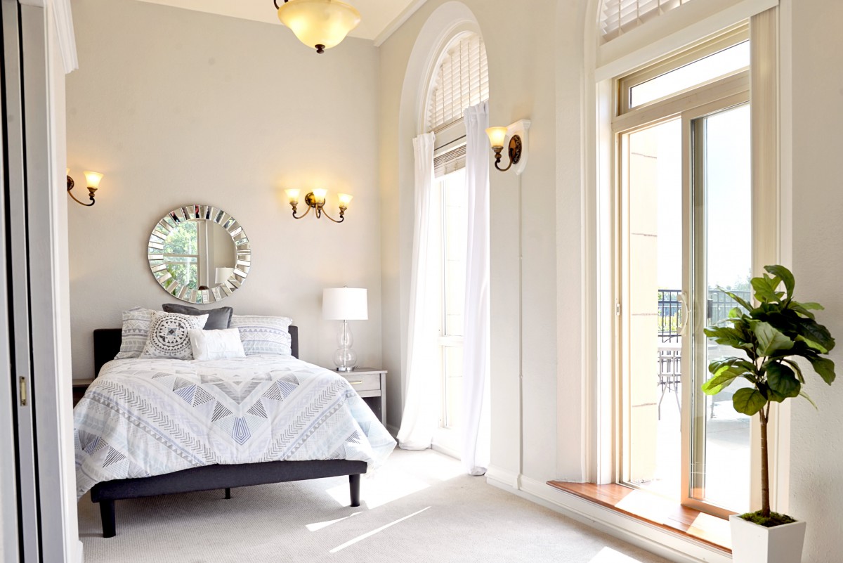 A bright and modern bedroom with elegant decor and large windows letting in natural light.