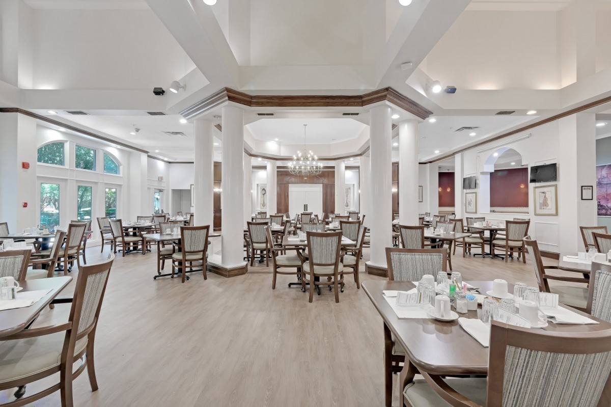 An elegant dining room with neatly arranged tables and chairs, illuminated by soft lighting.