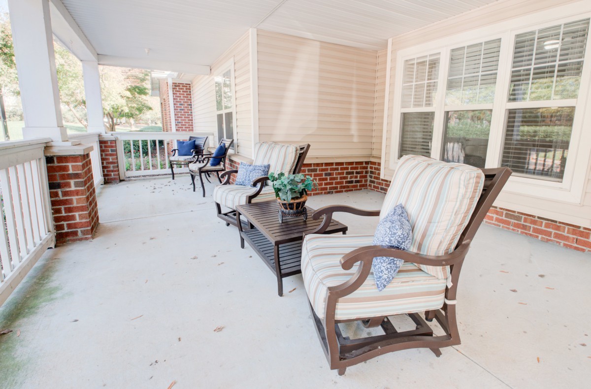 A cozy porch with comfortable seating and potted plants, perfect for relaxation.