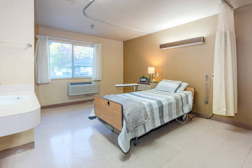 A clean and comfortable hospital patient room with a bed, window, and essential amenities.