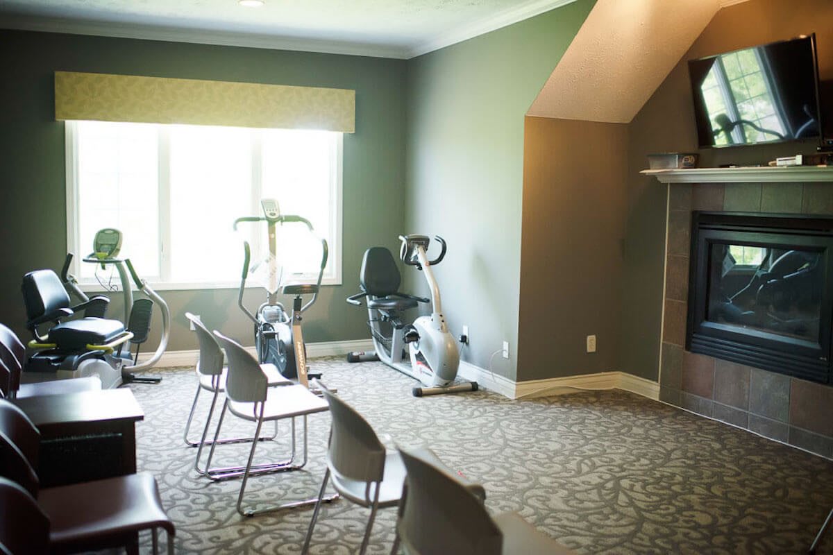 A small gym room with stationary bikes and chairs arranged neatly.