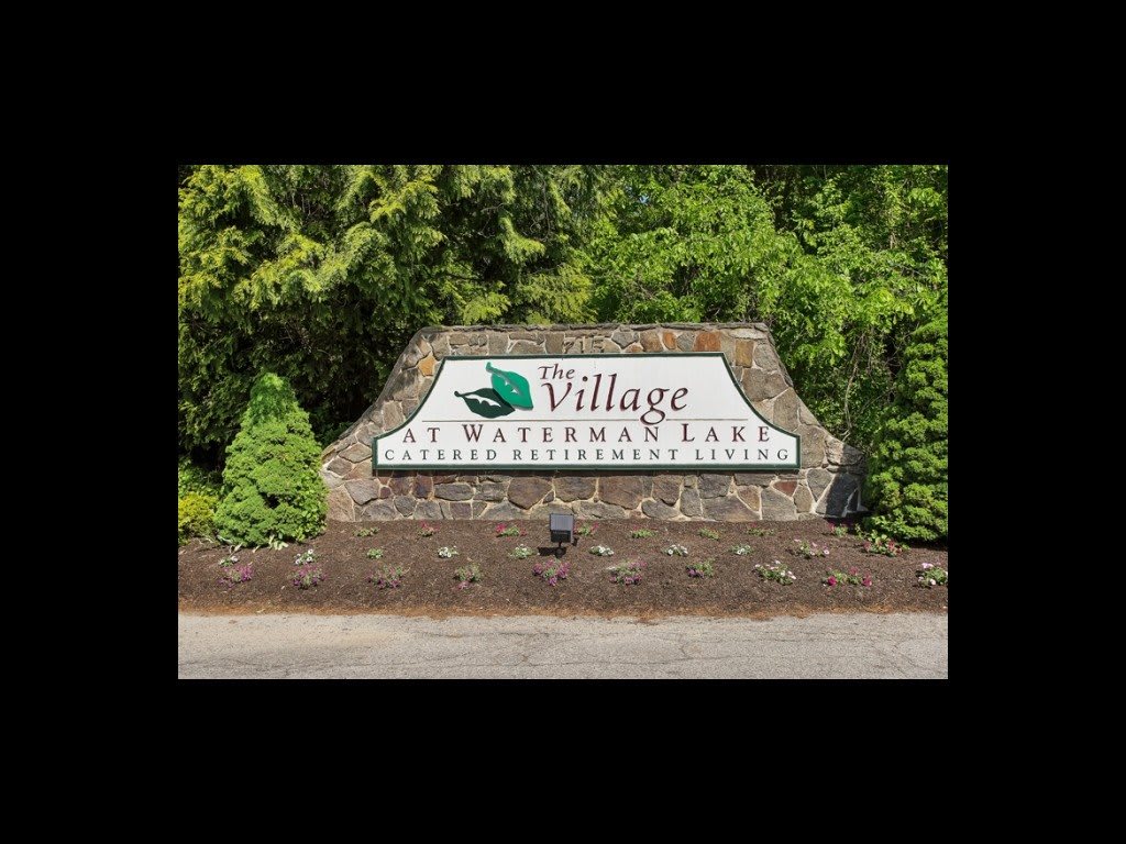 Entrance sign for The Village at Shawnee Lake surrounded by lush greenery.