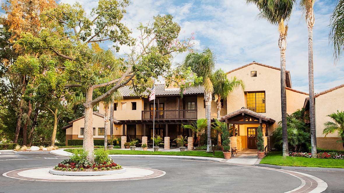 A residential building surrounded by trees and a circular driveway.