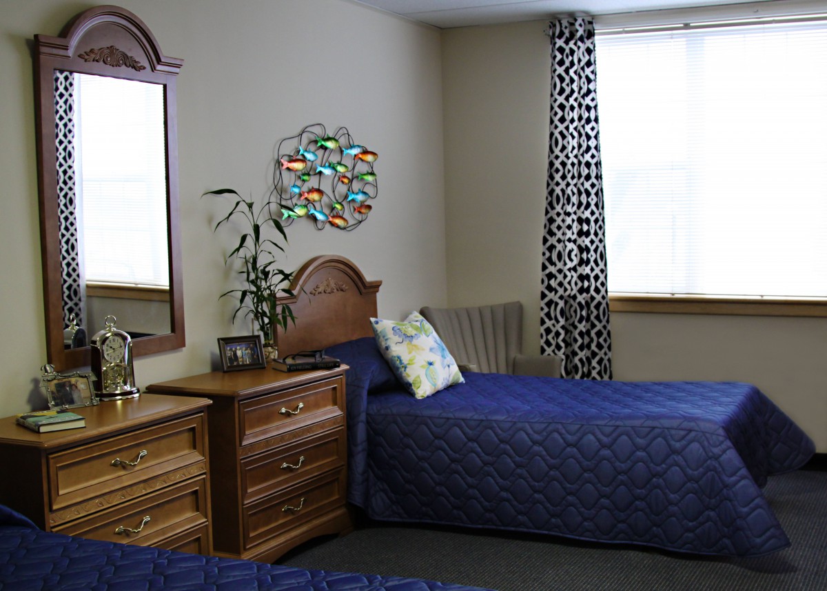 A cozy bedroom with two blue-covered beds and wooden furniture.