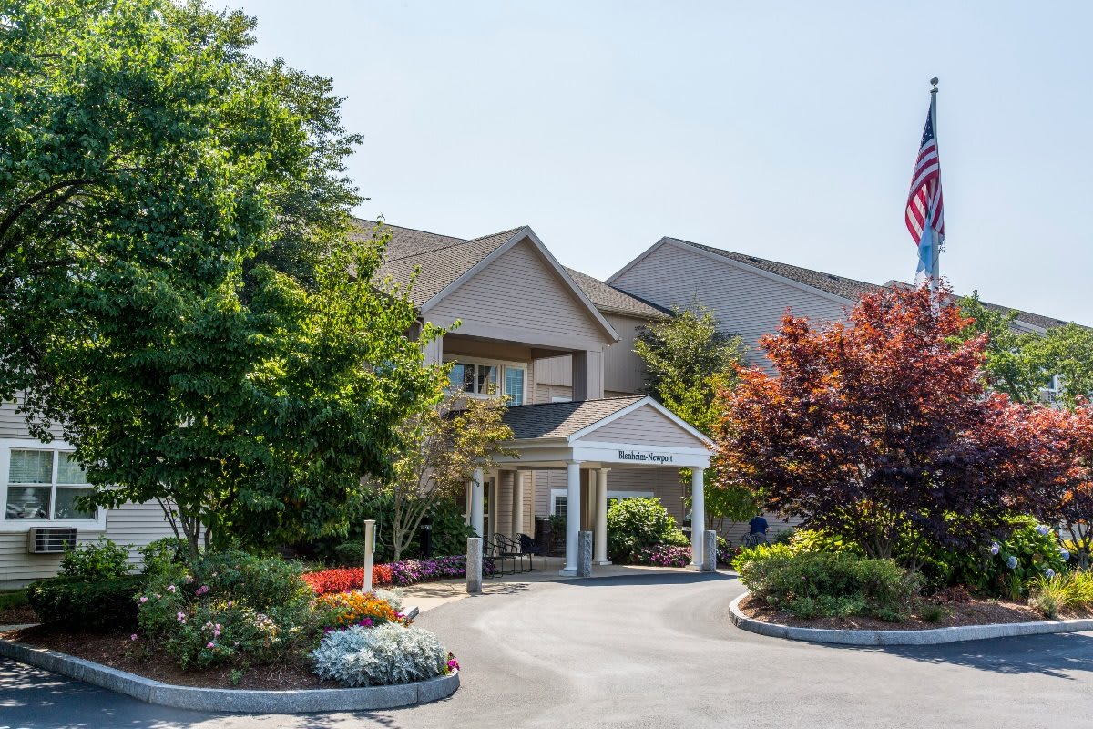 A building with a landscaped entrance surrounded by trees.