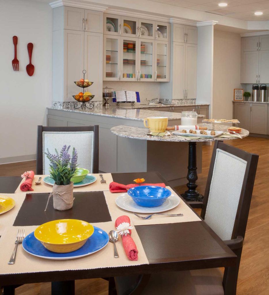 A modern dining area with a colorful table setting and an open kitchen in the background.