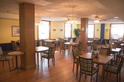 A spacious and well-lit dining area with wooden tables and chairs, ready for guests.