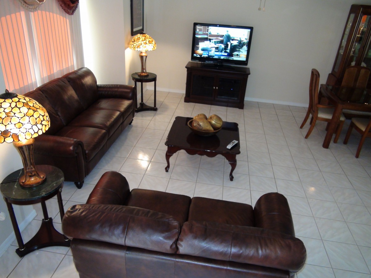 A cozy living room with leather sofas, a wooden coffee table, and a TV.