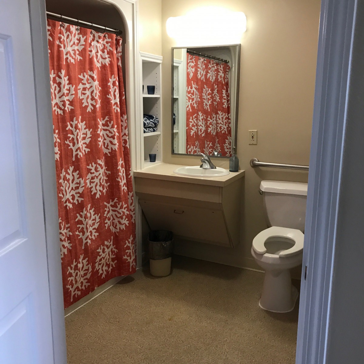 A clean bathroom with a red and white patterned shower curtain.