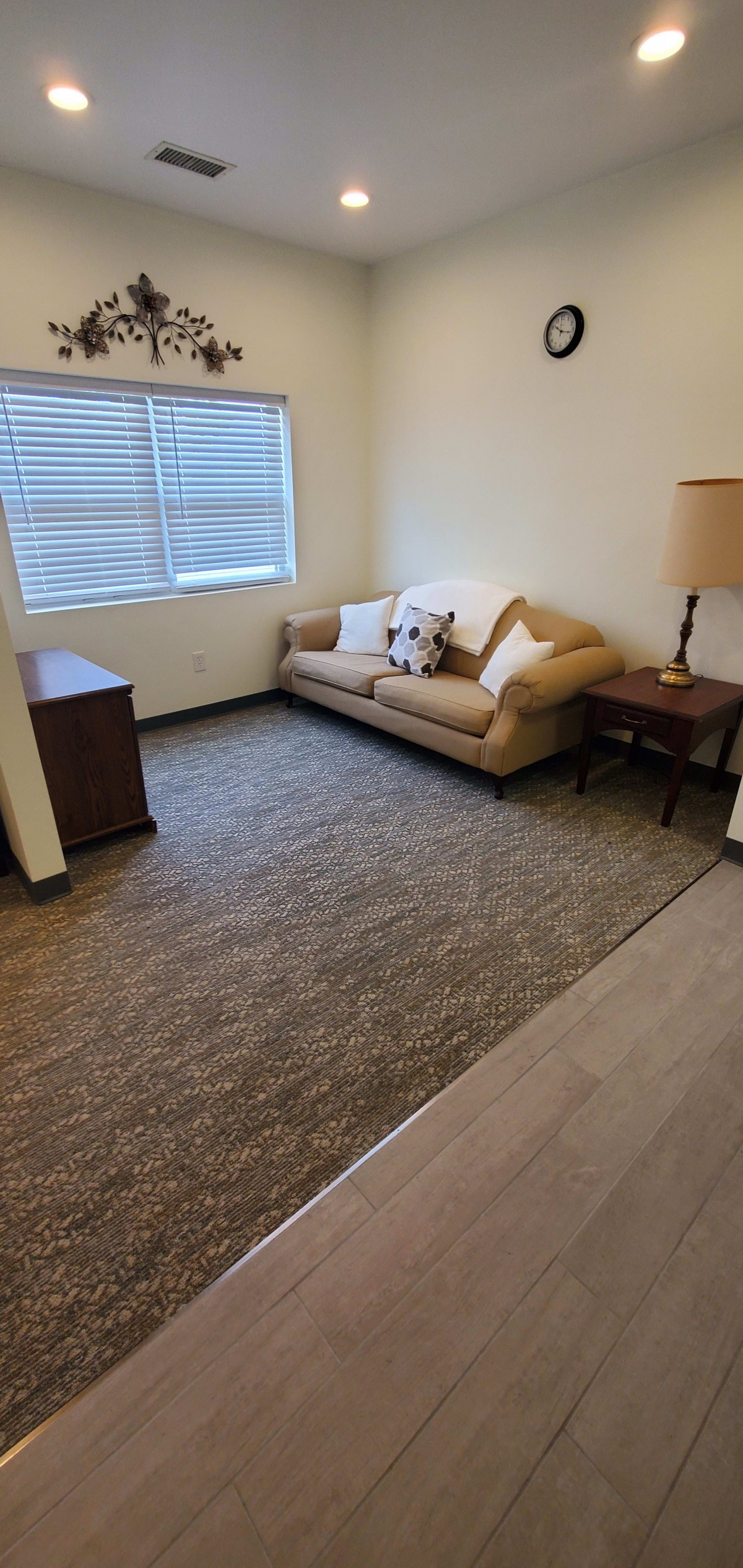 A cozy living room with a couch, side table, and lamp near a window.
