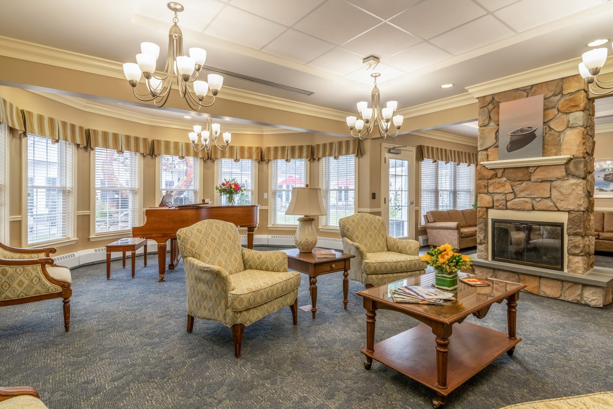 A beautifully decorated living room featuring elegant chandeliers, a warm fireplace, and comfortable seating in a traditional style.