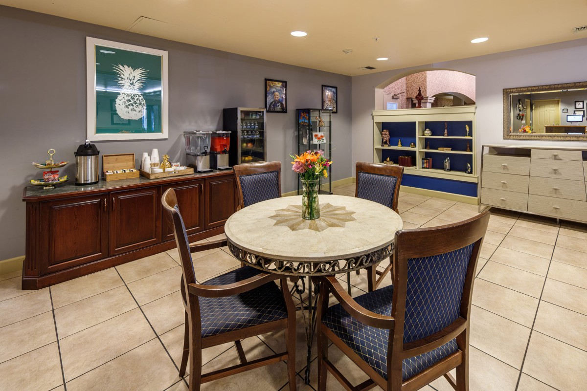 A cozy dining area with a round table and four chairs, adorned with flowers, set in a well-equipped kitchen space.