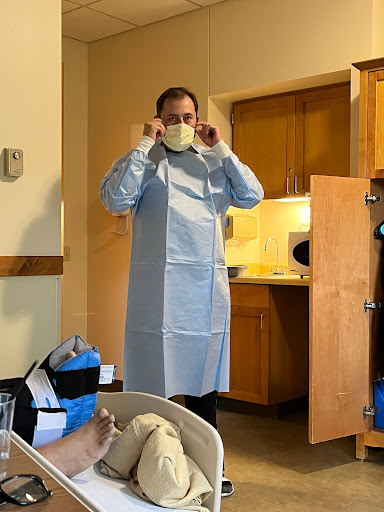 A healthcare worker prepares for a medical procedure, wearing a mask and surgical gown.
