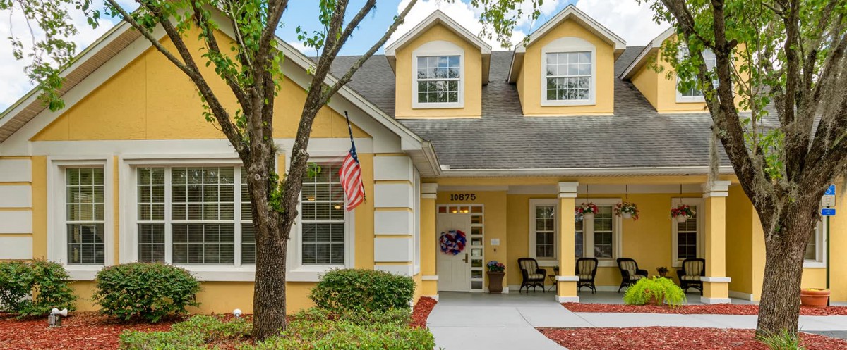 Charming yellow two-story house with a front porch and an American flag.