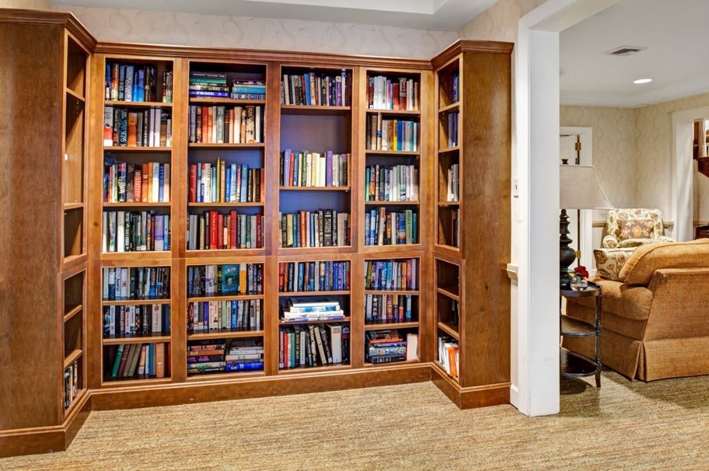 A cozy home library with a large wooden bookshelf filled with books.