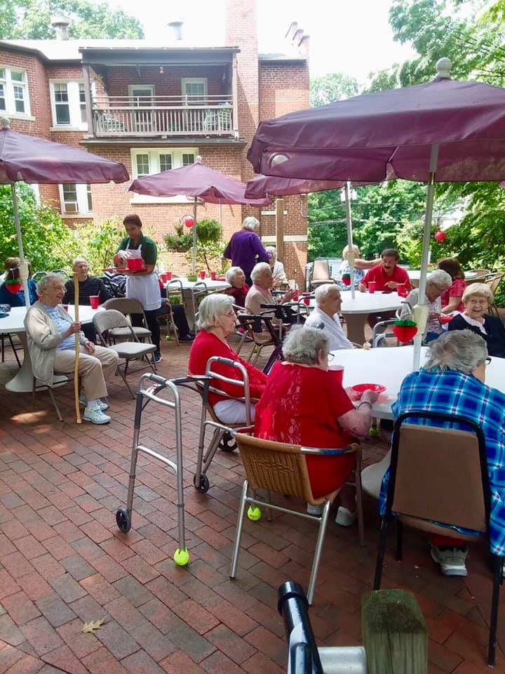 A group of seniors enjoying a social gathering in an outdoor garden setting.