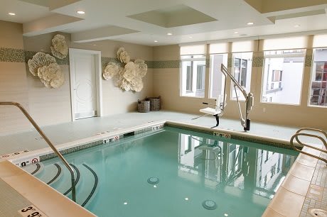 An indoor therapy pool with exercise equipment and soft lighting.