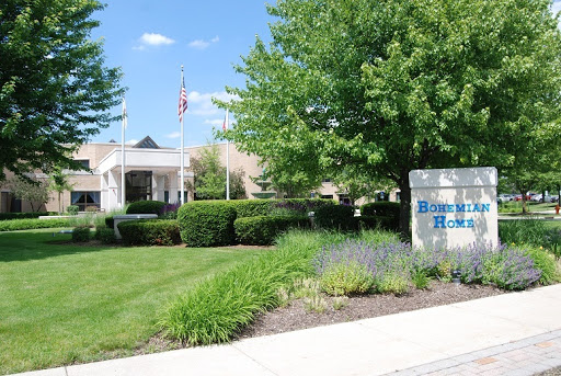 A well-maintained building surrounded by greenery and a clear blue sky.