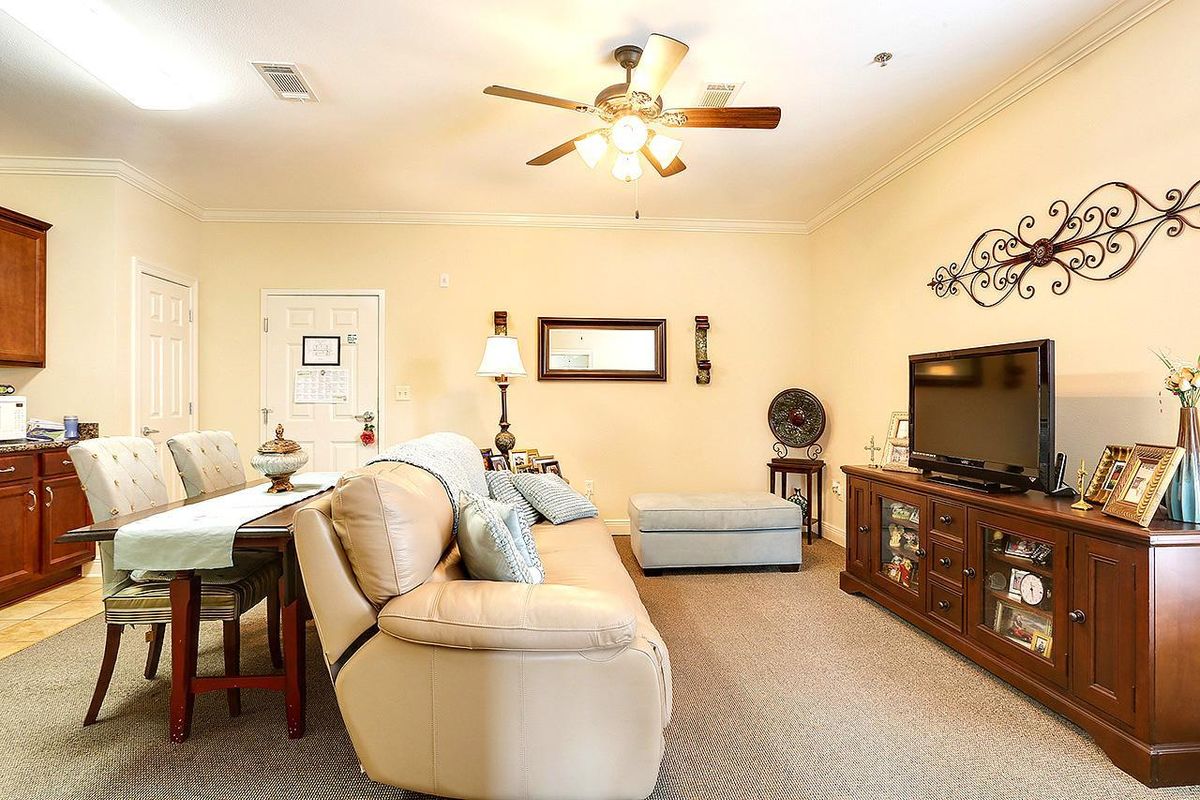 A cozy living room with a comfortable sofa, television, and ceiling fan.