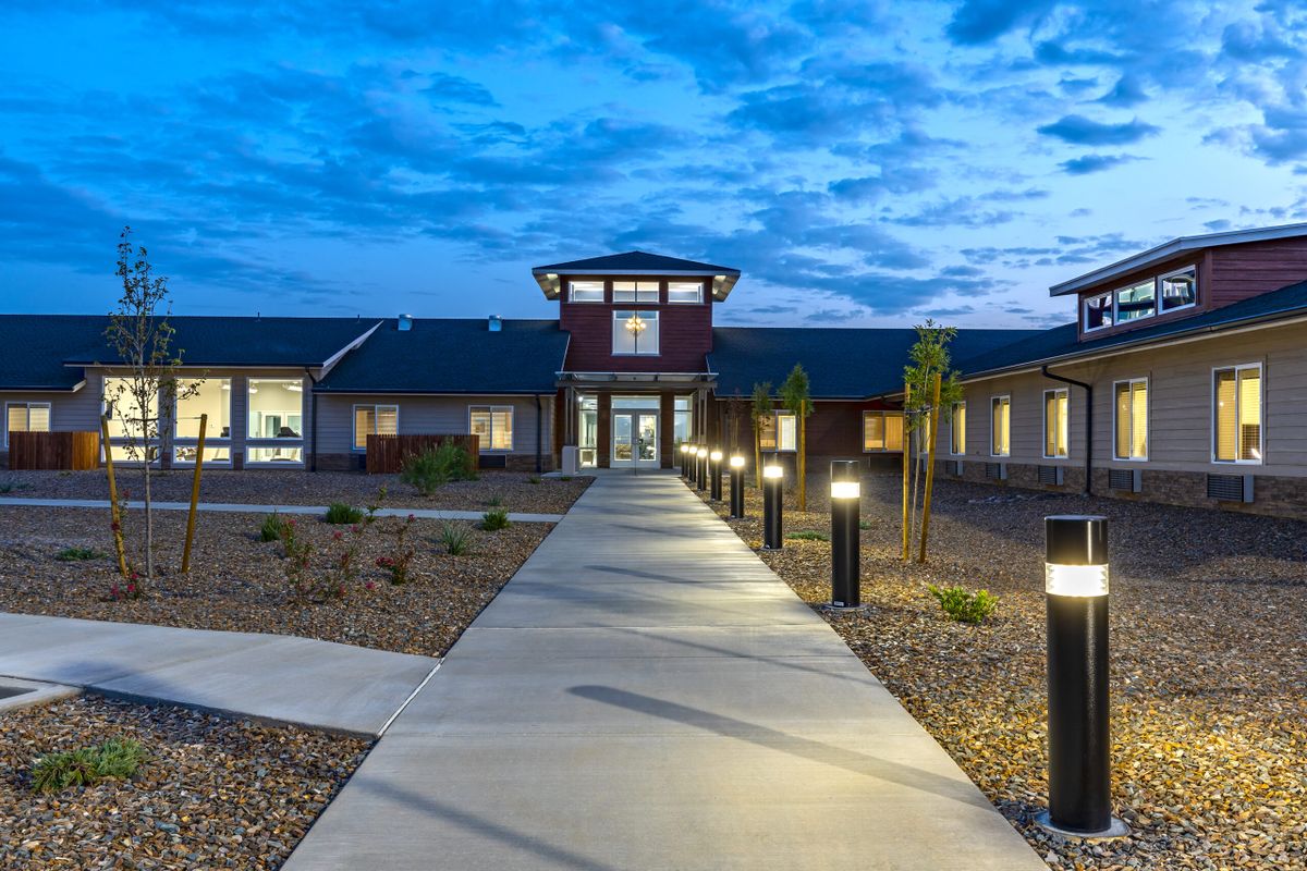 A modern building with a lit pathway during the evening.