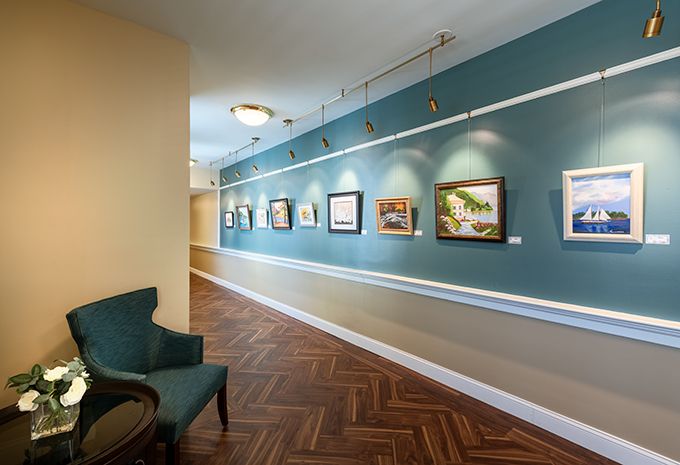 A modern art gallery with paintings displayed along a long hallway.