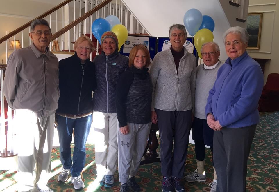 A group of people gathered indoors for a celebration with balloons.