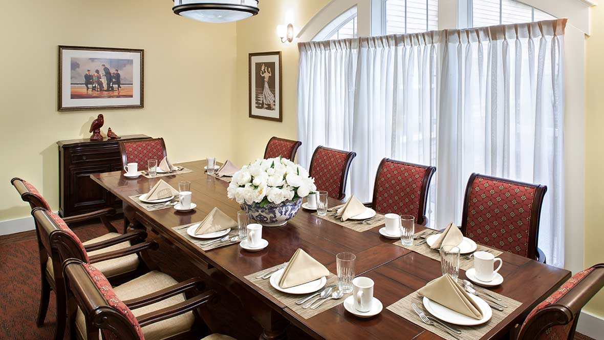 An elegantly set dining table with red chairs and a centerpiece of white flowers.