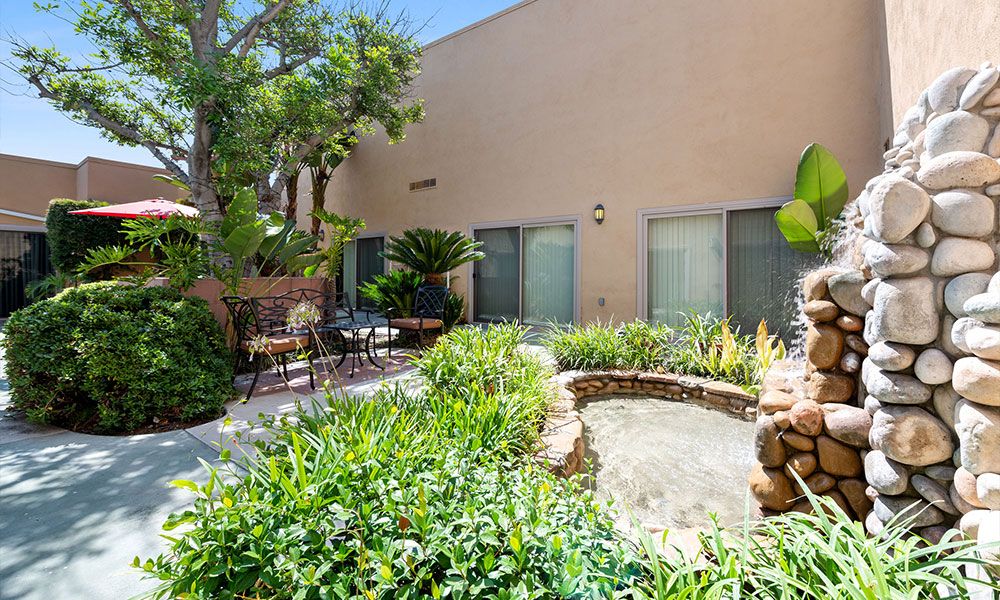 A peaceful garden patio with lush greenery and a small pond, offering a tranquil outdoor seating area.