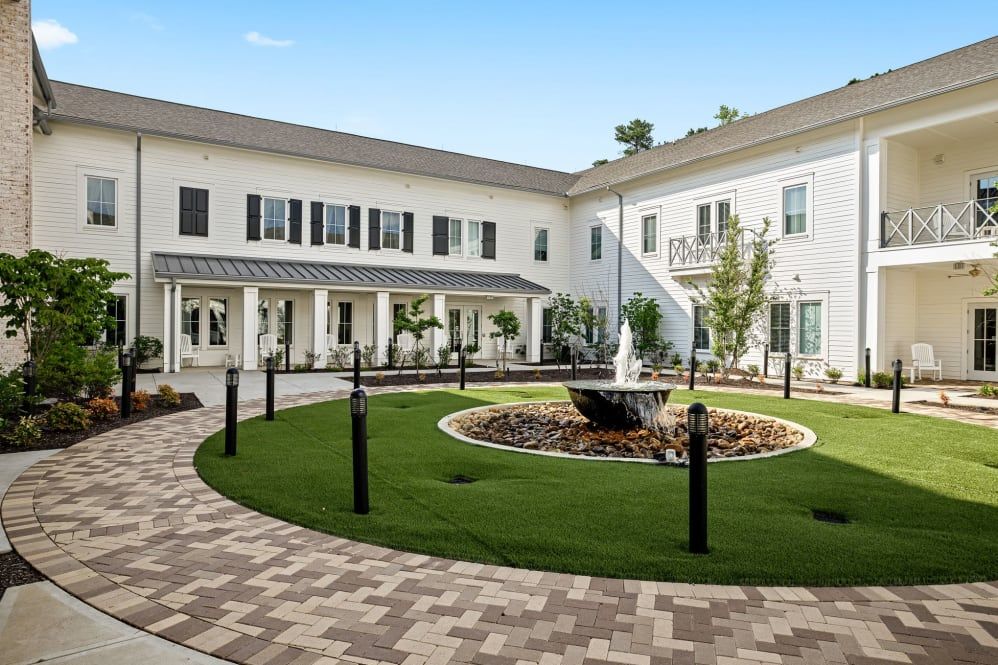 A view of a beautifully landscaped courtyard featuring a central fountain surrounded by grassy areas and a paved pathway.
