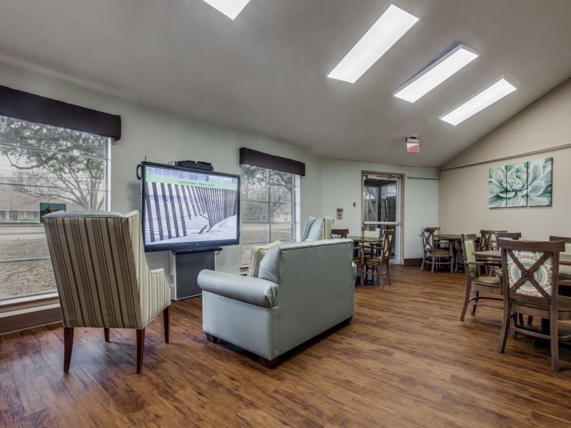 A cozy lounge area with comfortable seating and a large television, illuminated by natural light from overhead skylights.
