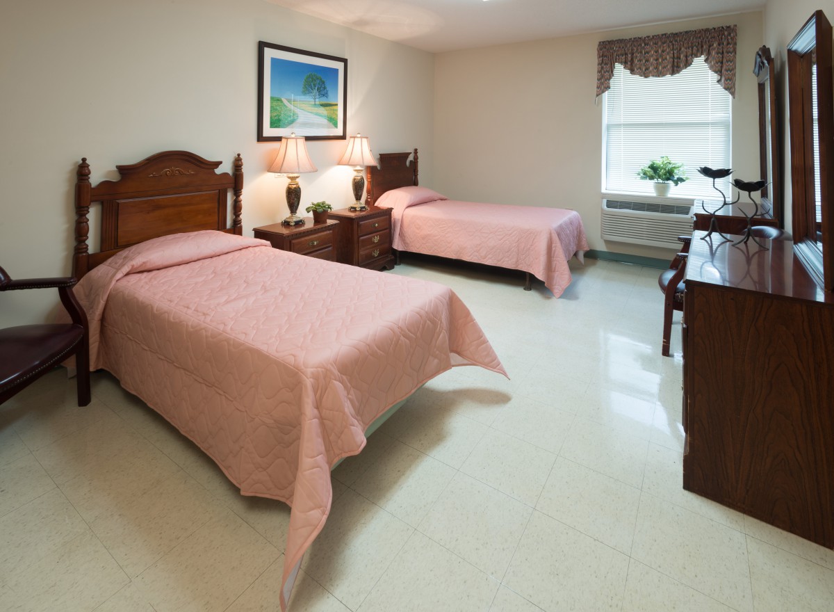 A neatly arranged bedroom with two twin beds, wooden furniture, and soft lighting.